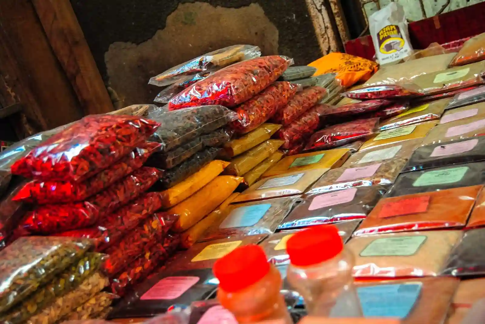 Bags of colorful spices and herbs displayed for sale at a market stall in Zanzibar.