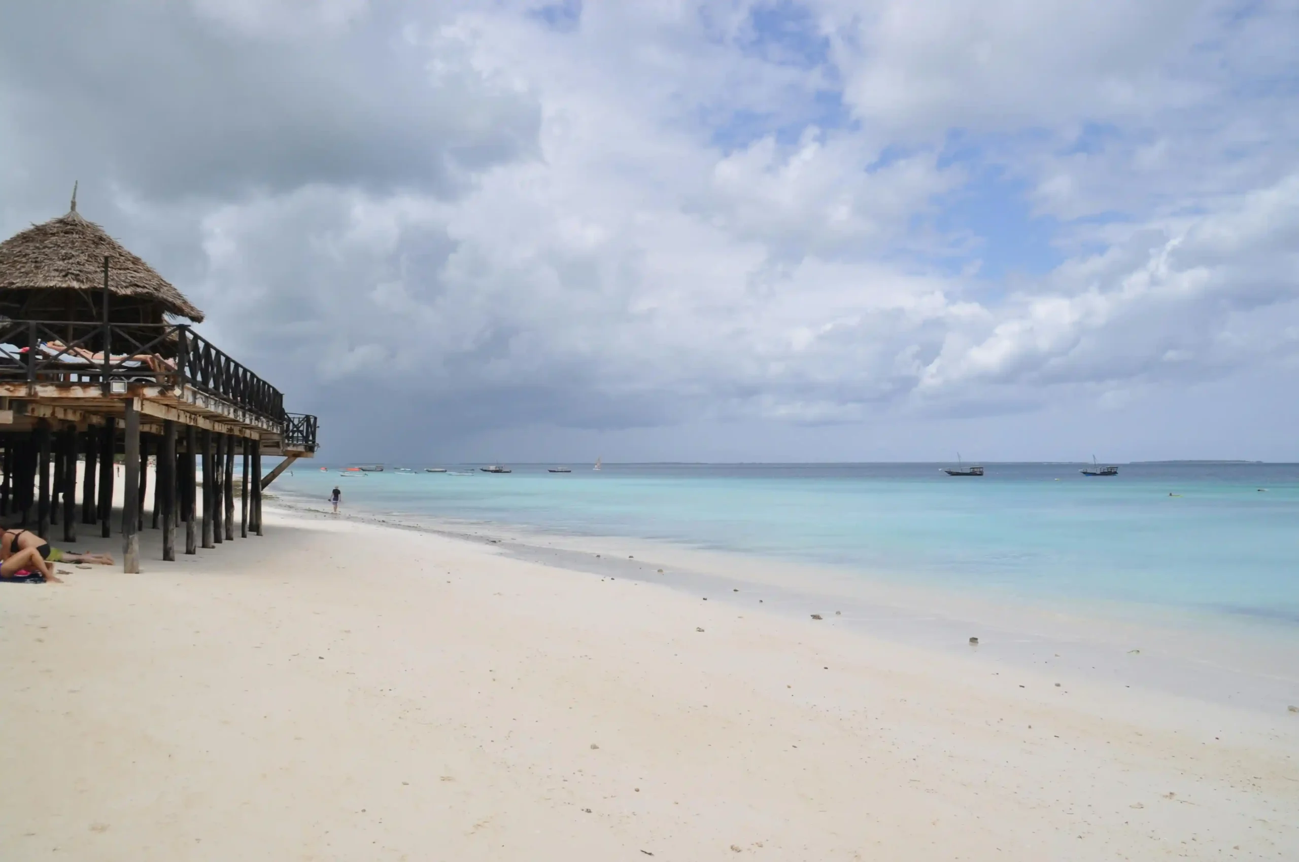A view of the white sand beach at Kendwa, Zanzibar, with a wooden pier extending over the turquoise ocean.