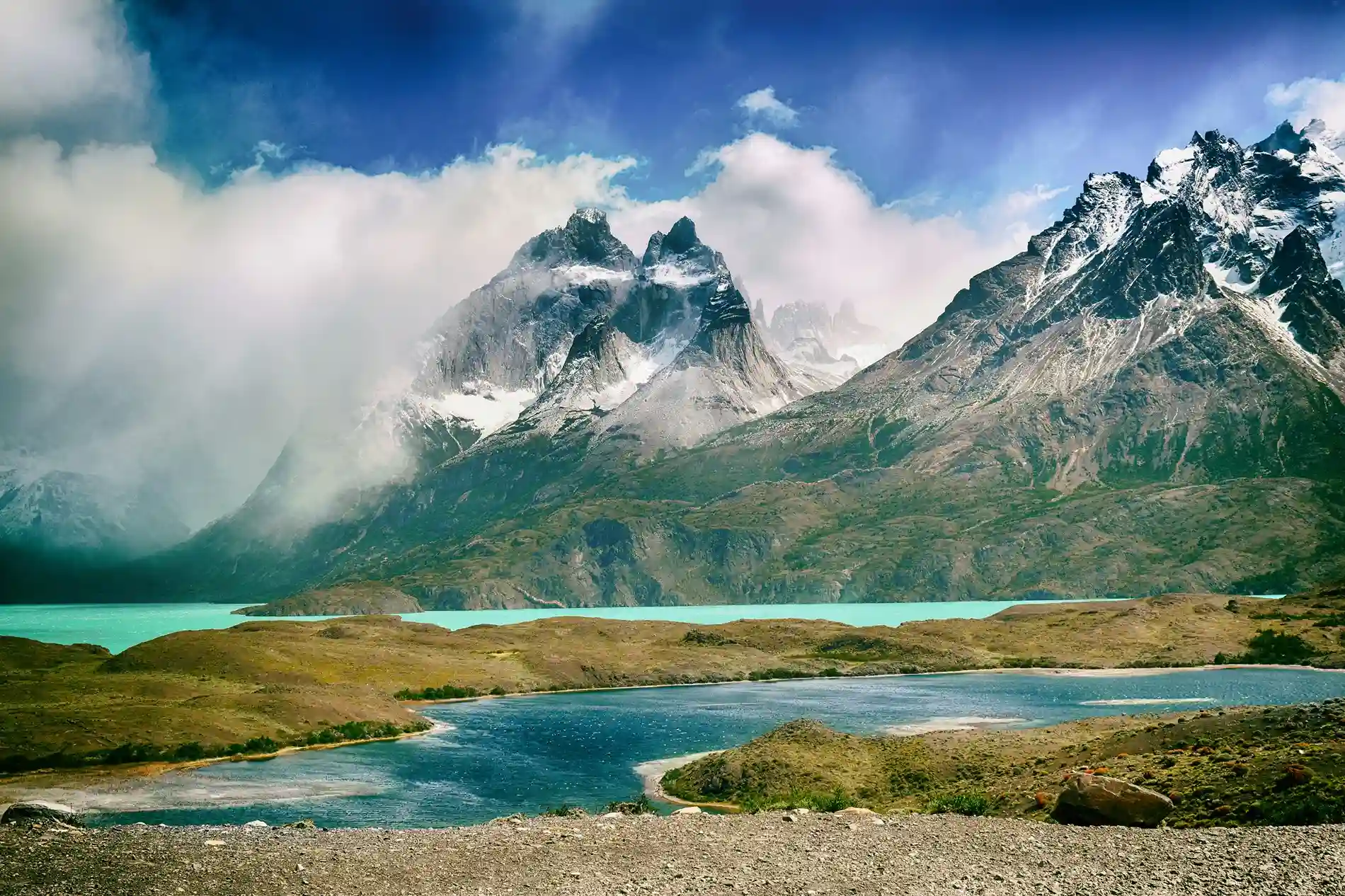 A scenic landscape of snow-capped mountains and a turquoise lake in Torres del Paine National Park, Patagonia, Chile.