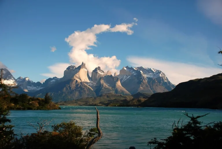 A scenic landscape of snow-capped mountains and a turquoise lake in Torres del Paine National Park, Patagonia, Chile.