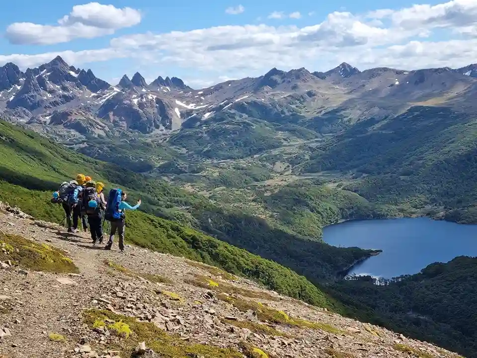 Hikers on the Dientes de Navarino trail with a view of the mountains and a lake, Patagonia, Chile.