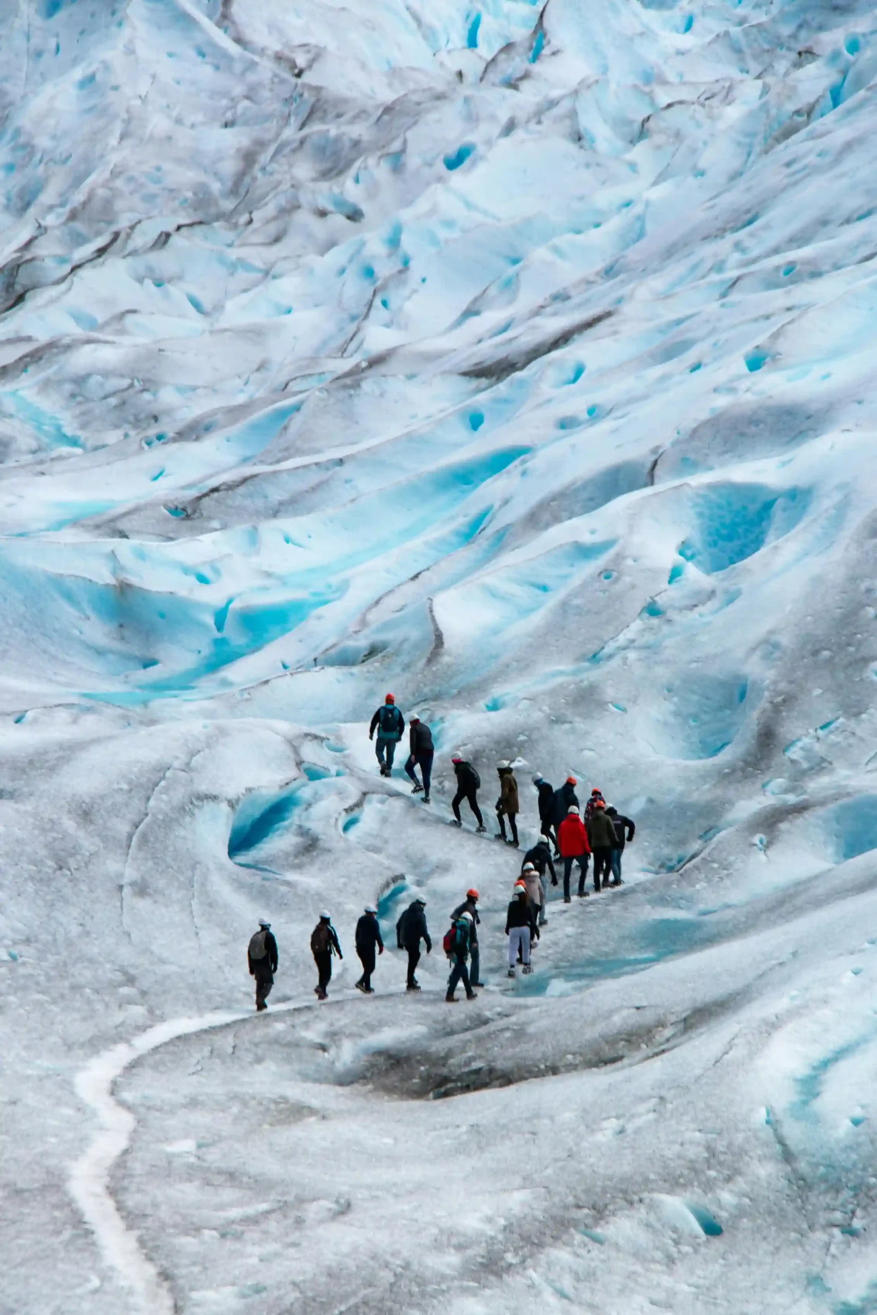 Trekkers hiking on the blue and white ice of the Perito Moreno Glacier, Los Glaciares National Park, Argentina.