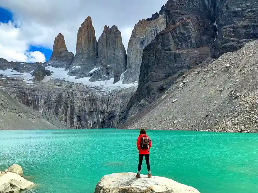 Hiker overlooking the turquoise lake at Mirador Las Torres in Torres del Paine, Patagonia.