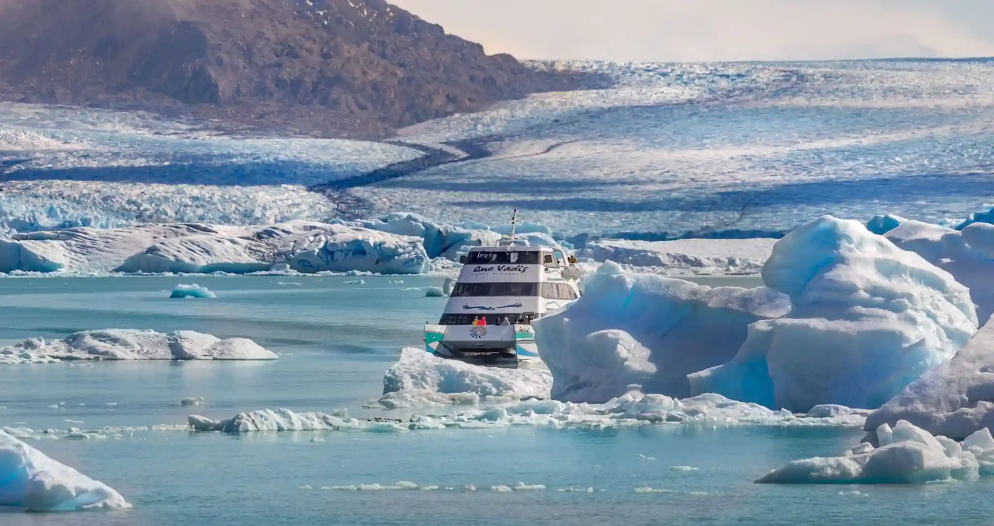 Boat navigating through icebergs toward a glacier on Lago Argentino near Perito Moreno in Patagonia.